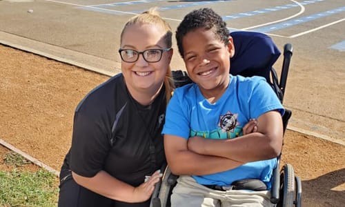 Tina and child in wheelchair smiling at the camera