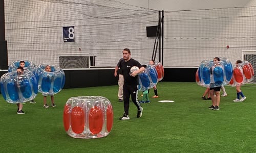 Kids playing indoor soccer in bubbles