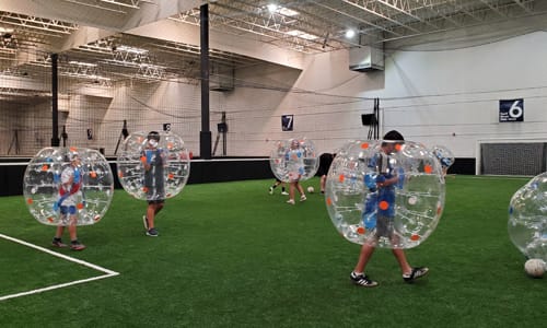 Kids playing indoor soccer in bubbles