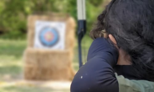 Girl shooting an arrow with a bow. Girl practicing Archery