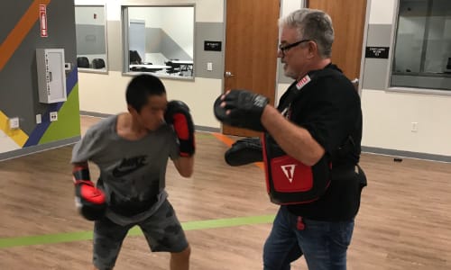 Kid working with boxing instructor