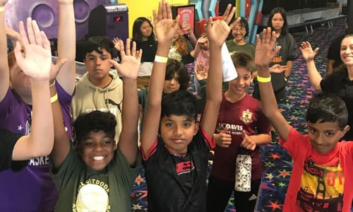 Group of kids with hands up in the air smiling