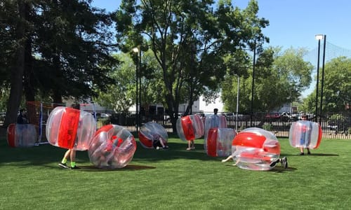 Group of kids playing outdoor bubble soccer